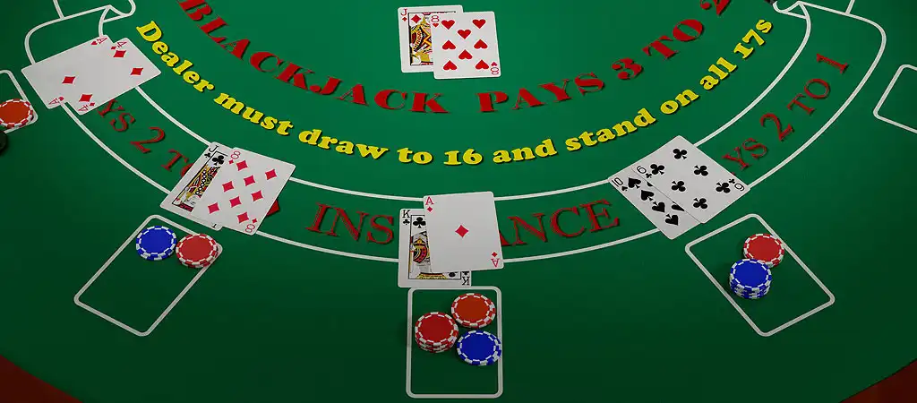 Blackjack asztal az osztó lapjaival és játékosok lapjaival és zsetonjaival.