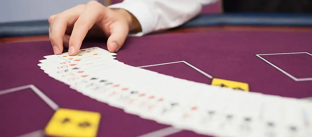 Blackjack osztó az asztalnál kártyákat oszt szét egy kaszinójáték során.