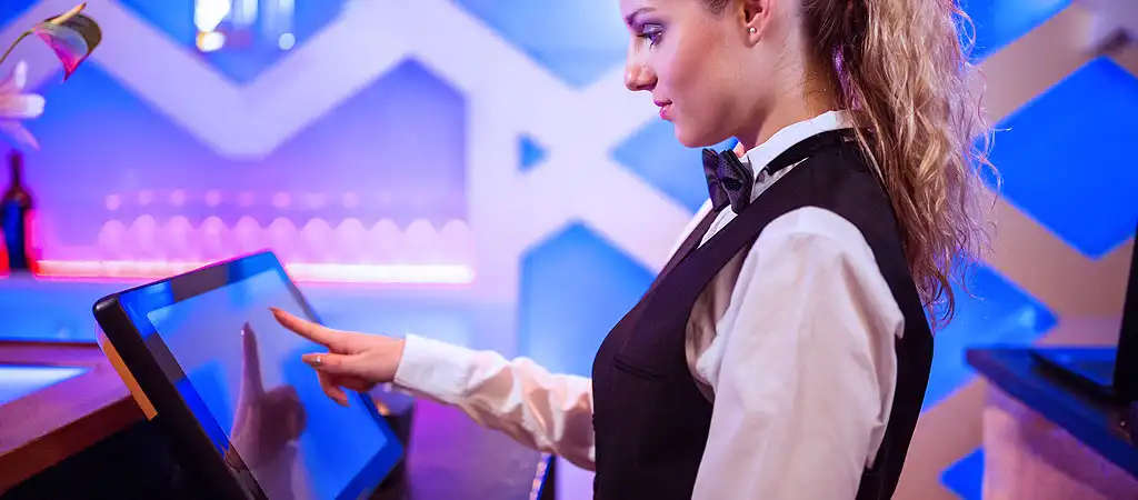 Egy elegáns krupié digitális érintőképernyőt kezel egy online élő kaszinóban.