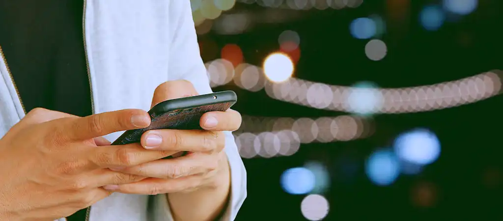 A játékos mobiltelefont használ, amely az élő kaszinók online elérhetőségét mutatja.