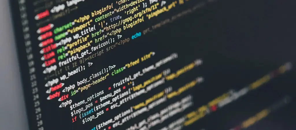 Programkód közelről egy sötét hátterű számítógépes képernyőn